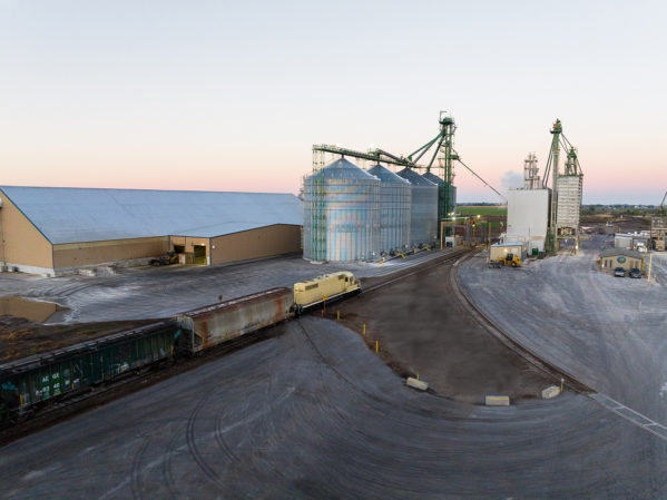 Aerial JDH Gooding, Idaho Mill. The sun is rising in the horizon and steam is coming off of the mills and silos.