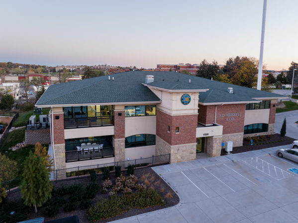 Brick building, that is JDH Omaha headquarters, with buildings and a sunrise sky behind.