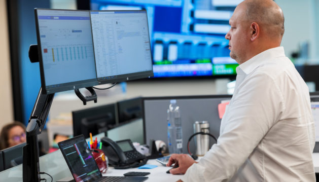 Employee standing at his computer, looking at his monitor